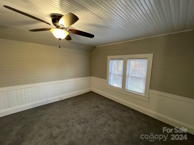 empty room with ceiling fan, lofted ceiling, and dark colored carpet