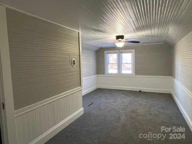 unfurnished room featuring dark carpet, vaulted ceiling, and ceiling fan