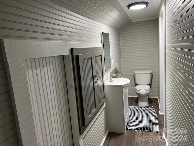 bathroom with hardwood / wood-style flooring, vanity, toilet, and lofted ceiling