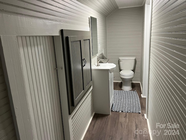 bathroom featuring vanity, wood-type flooring, lofted ceiling, and toilet