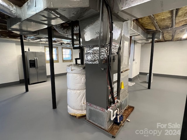 basement with heating unit and stainless steel fridge