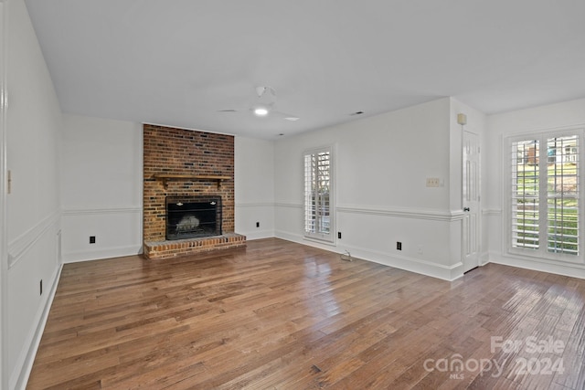 unfurnished living room featuring hardwood / wood-style floors, ceiling fan, and a fireplace