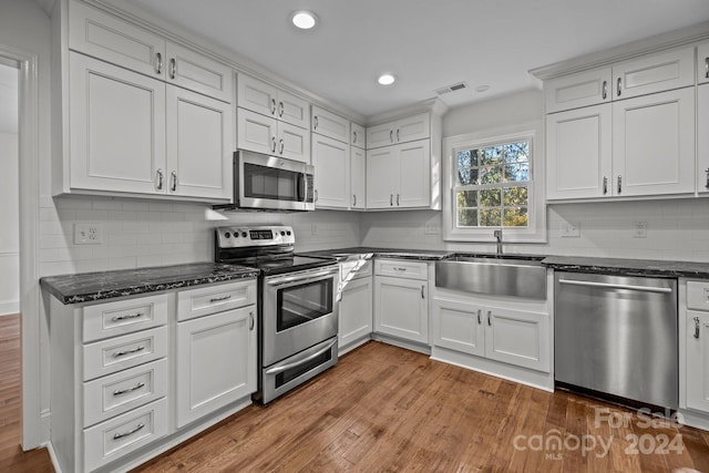 kitchen with wood-type flooring, white cabinetry, and stainless steel appliances