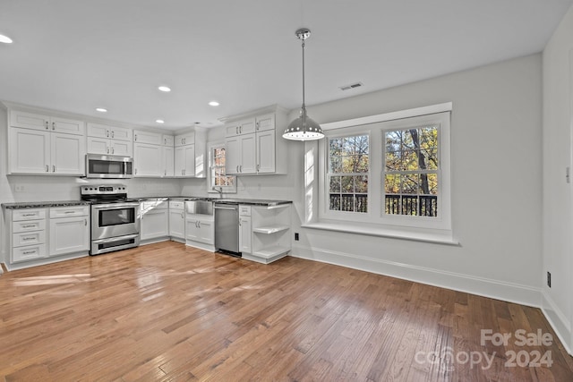 kitchen with white cabinets, pendant lighting, light hardwood / wood-style floors, and stainless steel appliances