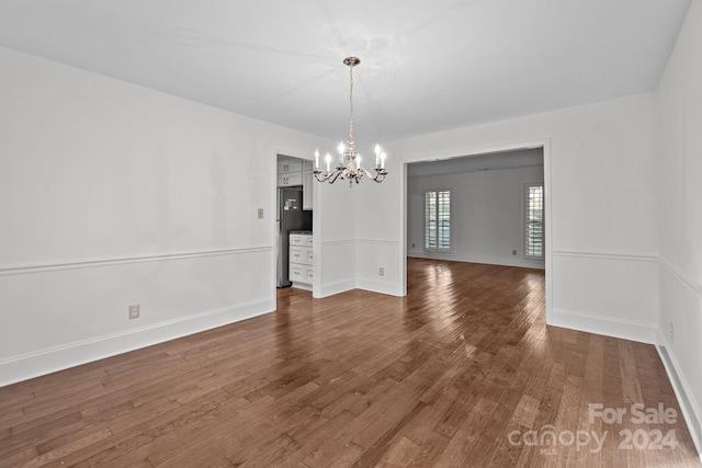 unfurnished dining area with dark wood-type flooring and a notable chandelier