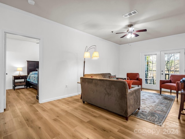 living room featuring ceiling fan, ornamental molding, and light wood-type flooring