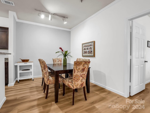 dining space with light wood-type flooring, rail lighting, and crown molding