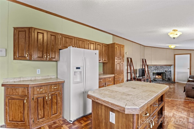 kitchen featuring tile counters, a kitchen island, white fridge with ice dispenser, and a textured ceiling