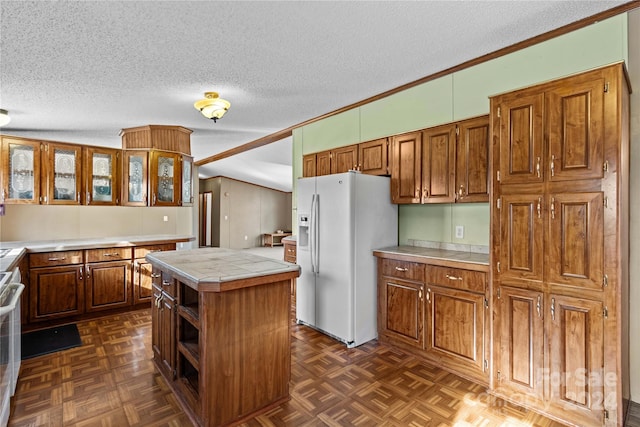 kitchen with dark parquet flooring, tile countertops, a textured ceiling, white appliances, and a kitchen island