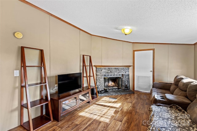 living room with crown molding, vaulted ceiling, dark hardwood / wood-style floors, a textured ceiling, and a fireplace