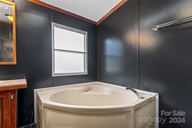 bathroom featuring ornamental molding, vanity, a textured ceiling, vaulted ceiling, and a tub