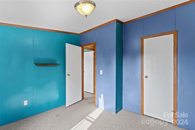 interior space with a textured ceiling, light colored carpet, and crown molding