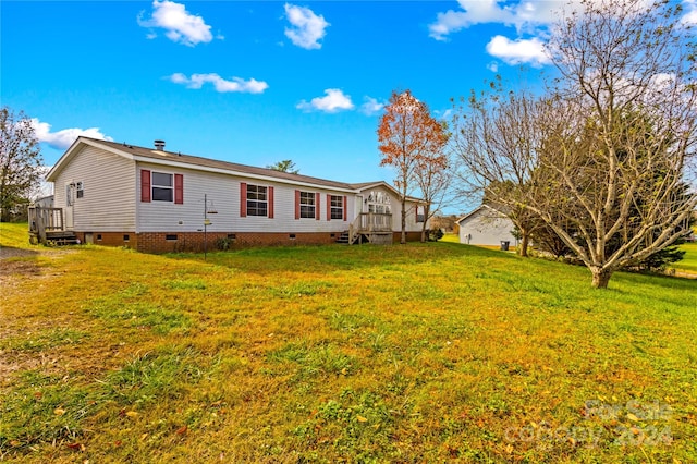 back of house featuring a lawn and a wooden deck