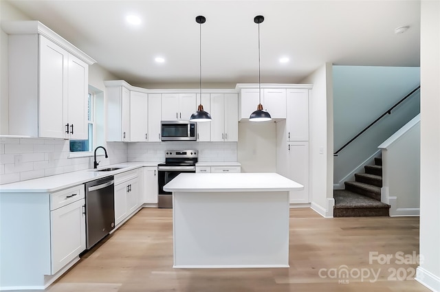 kitchen featuring pendant lighting, sink, a kitchen island, white cabinetry, and stainless steel appliances