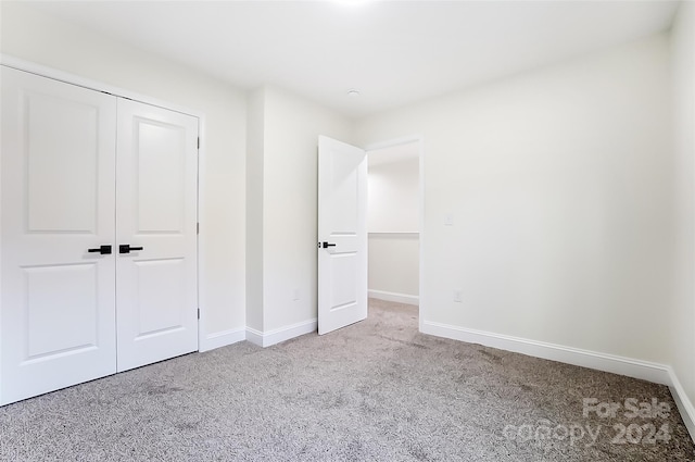 unfurnished bedroom featuring light colored carpet and a closet