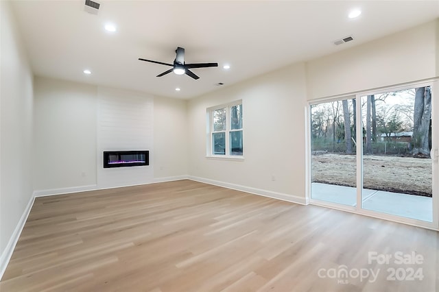 unfurnished living room with a fireplace, light wood-type flooring, plenty of natural light, and ceiling fan