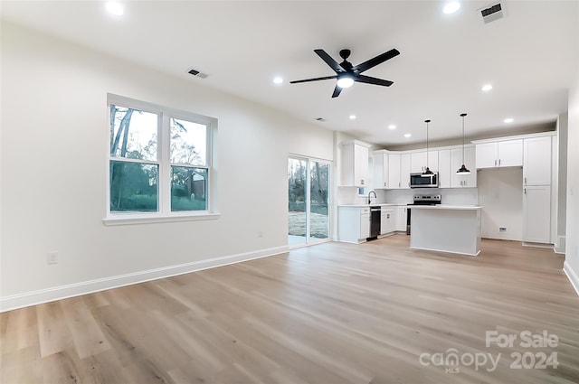 kitchen with hanging light fixtures, light hardwood / wood-style flooring, white cabinets, and stainless steel appliances