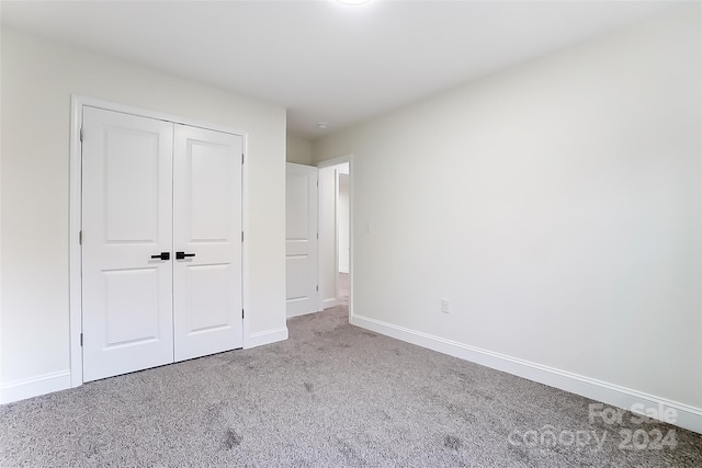 unfurnished bedroom featuring light colored carpet and a closet