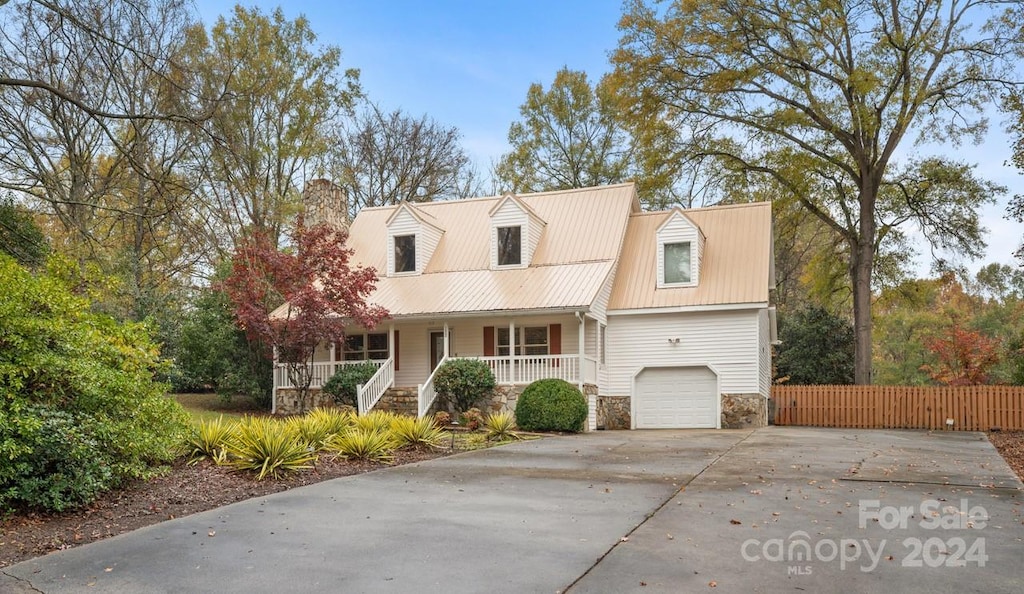 cape cod-style house featuring covered porch and a garage