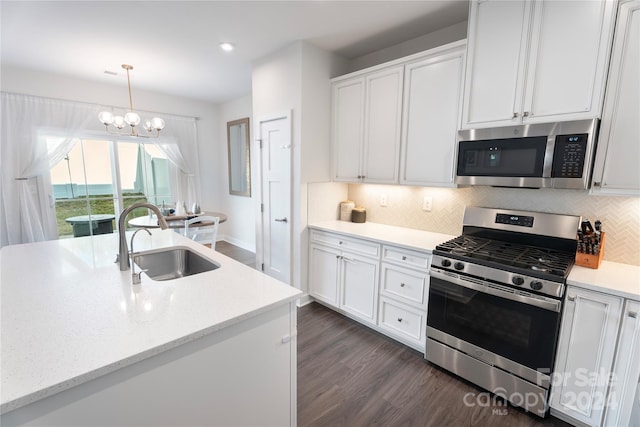 kitchen featuring a chandelier, pendant lighting, stainless steel appliances, and white cabinets