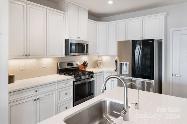 kitchen with white cabinets, appliances with stainless steel finishes, backsplash, and light stone counters