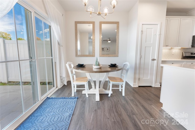 dining area with ceiling fan with notable chandelier and dark hardwood / wood-style flooring