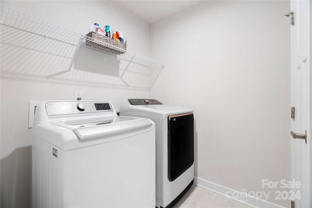 clothes washing area with light tile patterned flooring and independent washer and dryer