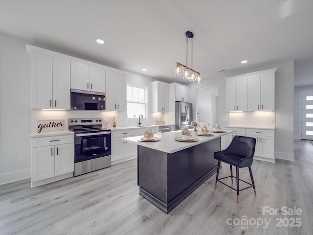 kitchen with white cabinetry, appliances with stainless steel finishes, a kitchen island, pendant lighting, and sink