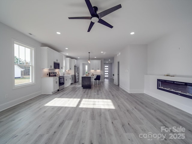 unfurnished living room featuring ceiling fan and light wood-type flooring