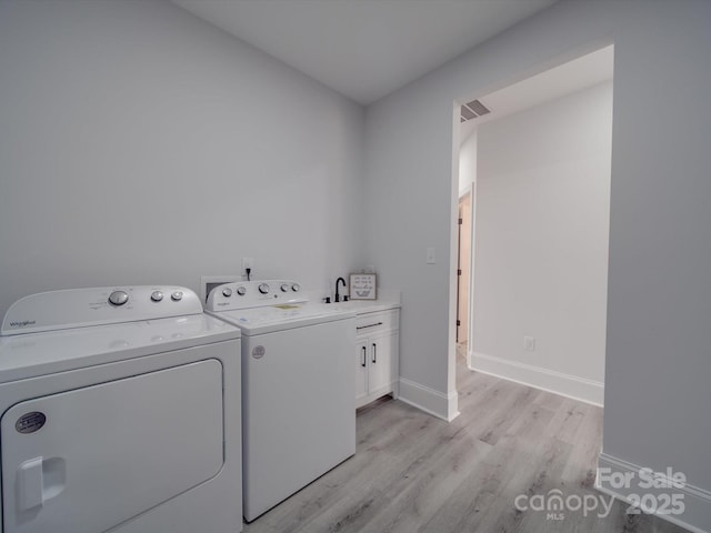 washroom featuring cabinets, separate washer and dryer, sink, and light hardwood / wood-style flooring