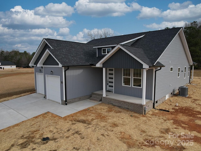 view of front of home with a garage, cooling unit, and covered porch