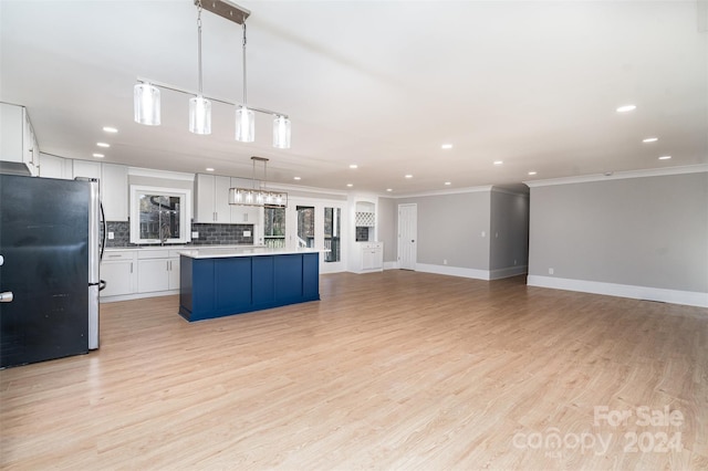 kitchen with white cabinets, light hardwood / wood-style floors, stainless steel refrigerator, and hanging light fixtures