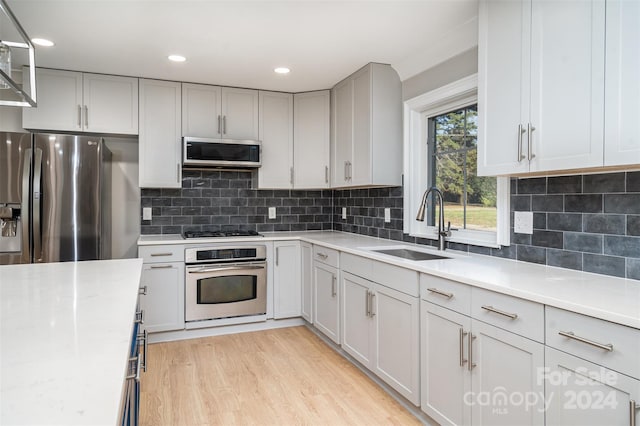 3700 Pinecrest Dr, Gastonia, NC 28056 - kitchen with stainless steel appliances, a sink, light countertops, light wood finished floors, and decorative backsplash