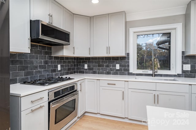 kitchen with decorative backsplash, sink, light wood-type flooring, and stainless steel appliances