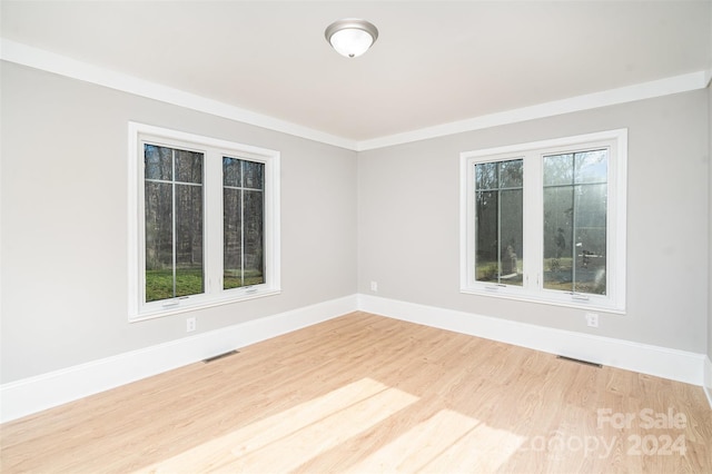 spare room with light wood-type flooring and ornamental molding