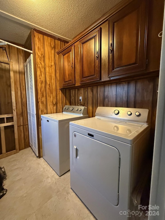 laundry area with cabinets, separate washer and dryer, and wooden walls