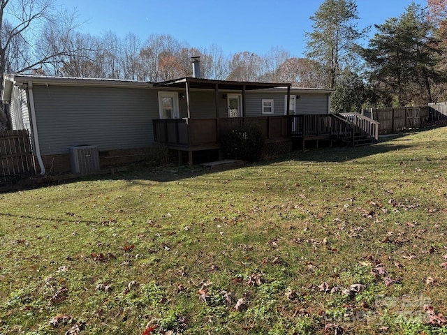 rear view of house featuring a yard, central air condition unit, and a wooden deck