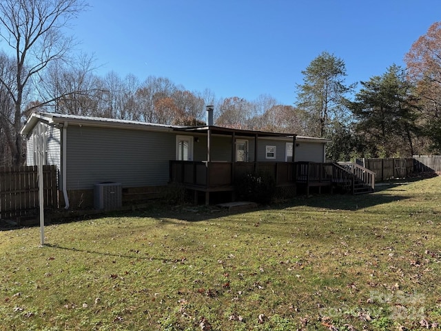 rear view of property with a lawn, a deck, and central AC