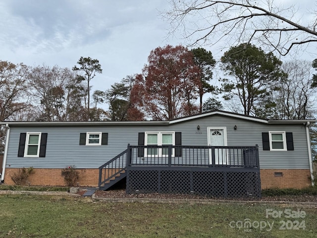 rear view of house featuring a wooden deck and a yard