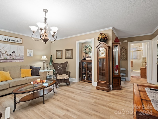 living room featuring a chandelier, light hardwood / wood-style floors, a textured ceiling, and ornamental molding