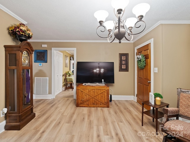 living room with a chandelier, a textured ceiling, light hardwood / wood-style floors, and crown molding