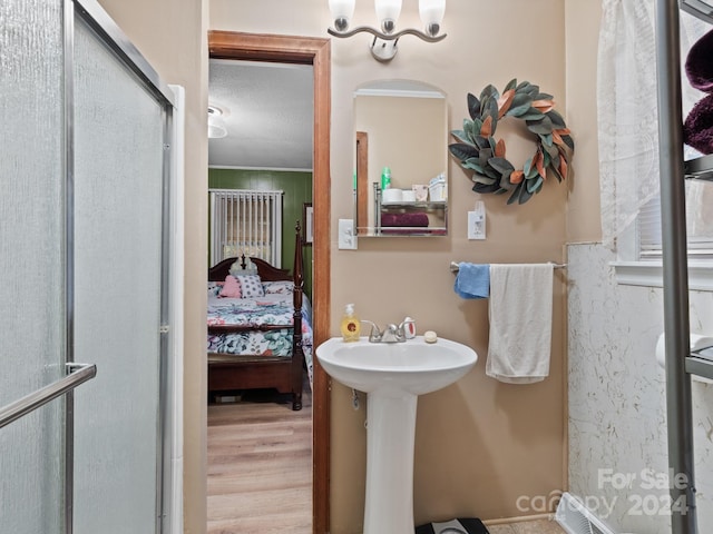 bathroom with hardwood / wood-style floors, a shower with door, and a textured ceiling