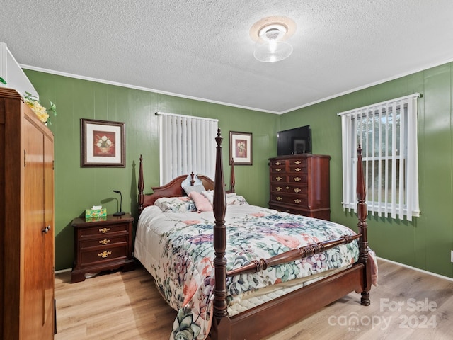 bedroom featuring crown molding, a textured ceiling, and light wood-type flooring