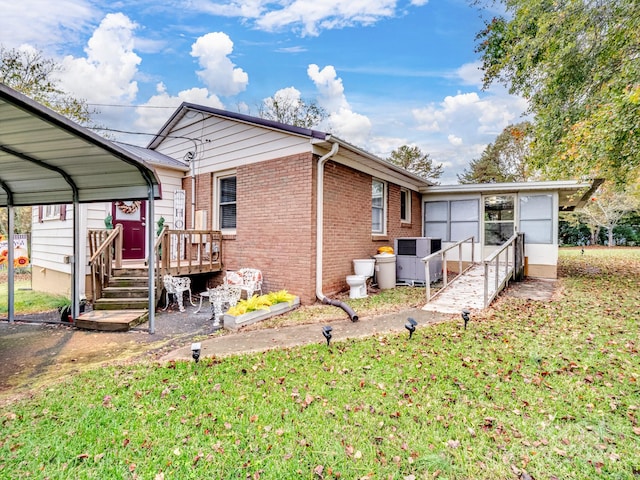 back of property with central air condition unit, a carport, and a lawn