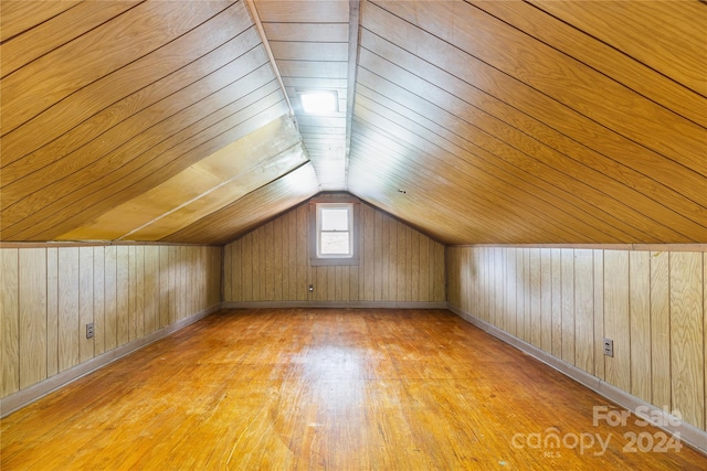 additional living space featuring lofted ceiling, wood walls, light wood-type flooring, and wood ceiling