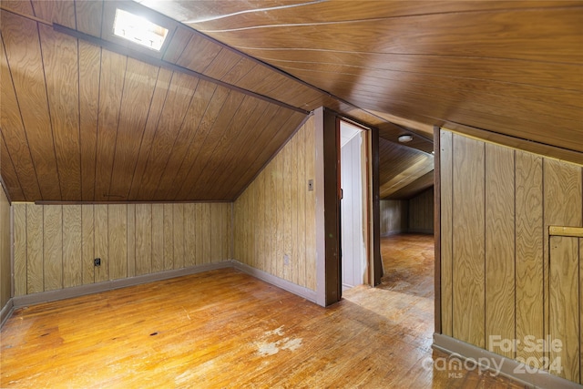 additional living space featuring light wood-type flooring, vaulted ceiling, wooden ceiling, and wood walls