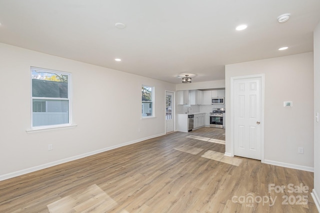 unfurnished living room featuring light wood-type flooring and sink