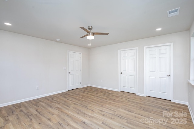 unfurnished bedroom with ceiling fan, light hardwood / wood-style floors, and two closets