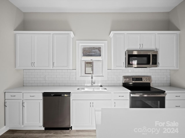 kitchen featuring hardwood / wood-style floors, appliances with stainless steel finishes, white cabinetry, and sink