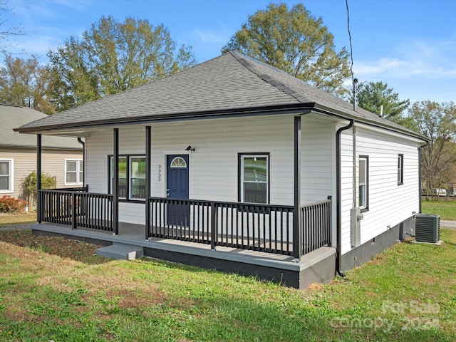 rear view of house with central AC unit, covered porch, and a yard